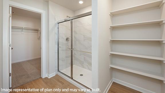 8313 NW 61st St, Oklahoma City, OK 73132 - full bathroom featuring a walk in closet, baseboards, wood finished floors, and a shower stall