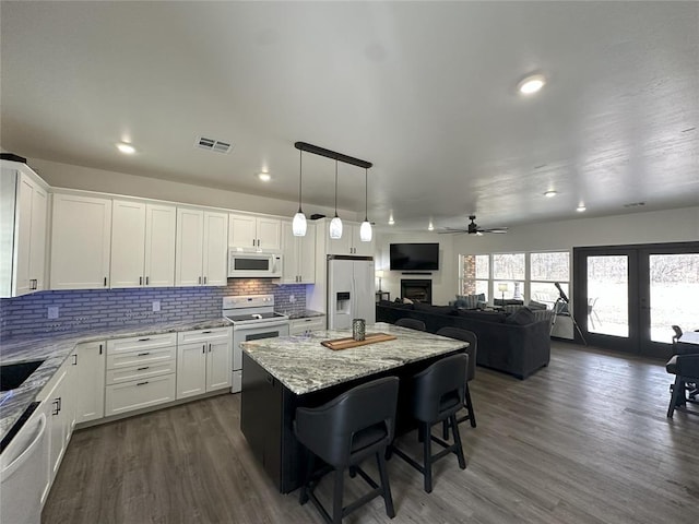 114495 S 4296th Rd, Porum, OK 74455 - kitchen featuring a breakfast bar area, light stone countertops, a center island, white appliances, and visible vents