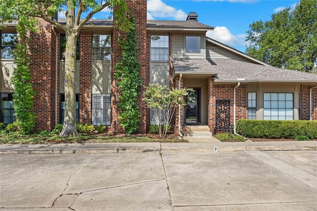 6204 Waterford Blvd Unit 2B, Oklahoma City, OK 73118 - view of front facade with brick siding, roof with shingles, and a chimney