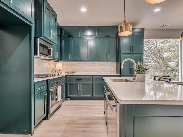 kitchen featuring green cabinets, a sink, and appliances with stainless steel finishes