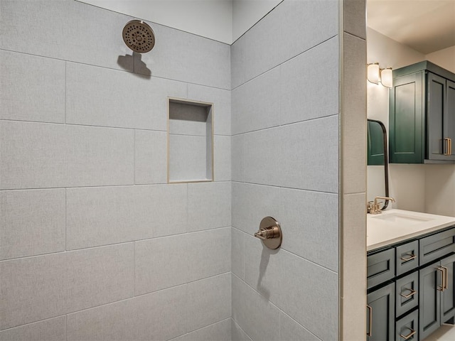 full bath featuring tiled shower and vanity