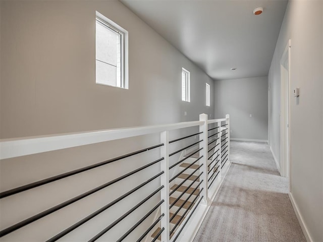 corridor with light carpet, baseboards, and an upstairs landing