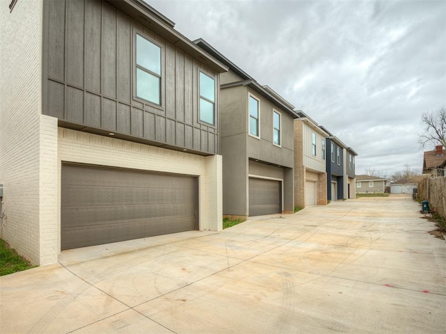 view of side of home with concrete driveway, stucco siding, an attached garage, board and batten siding, and brick siding