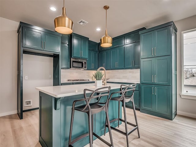 1308 NW 11th St, Oklahoma City, OK 73106 - kitchen with stainless steel microwave, tasteful backsplash, light countertops, light wood-style flooring, and recessed lighting