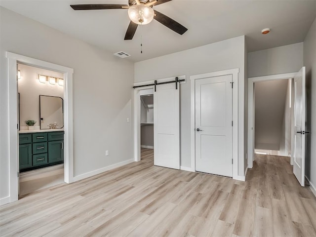 1308 NW 11th St, Oklahoma City, OK 73106 - unfurnished bedroom with light wood finished floors, a barn door, baseboards, and ensuite bath