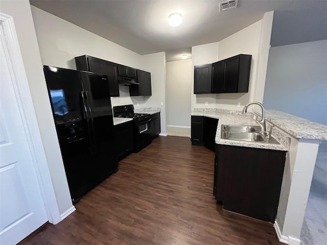 kitchen featuring visible vents, a sink, black appliances, a peninsula, and dark cabinetry