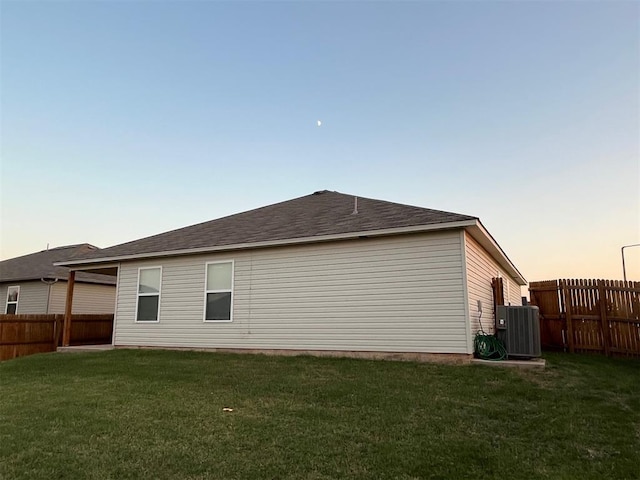 property exterior at dusk with a yard, cooling unit, and a fenced backyard