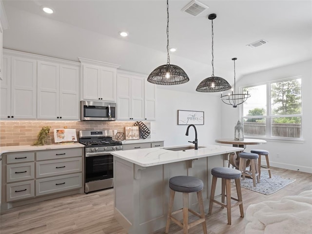 12712 NW 1st Ct, Yukon, OK 73099 - kitchen with appliances with stainless steel finishes, a sink, decorative backsplash, a kitchen island with sink, and a chandelier