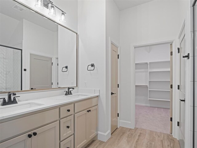 12712 NW 1st Ct, Yukon, OK 73099 - bathroom featuring a shower stall, double vanity, a spacious closet, wood finished floors, and baseboards