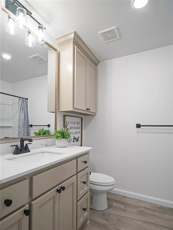 12712 NW 1st Ct, Yukon, OK 73099 - bathroom with vanity, toilet, wood finished floors, curtained shower, and baseboards