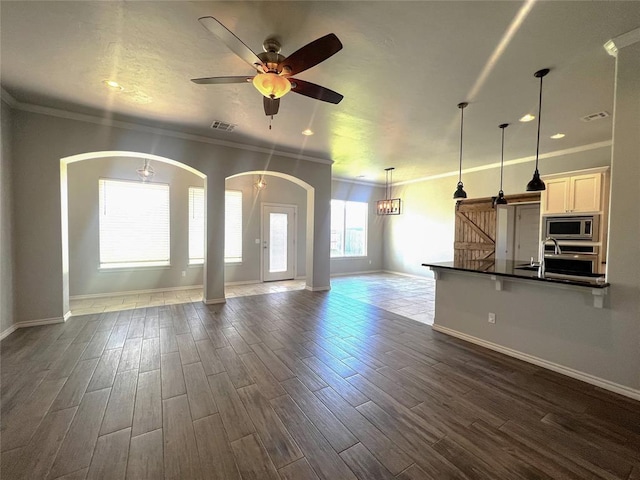 unfurnished living room featuring arched walkways, a barn door, baseboards, dark wood-style floors, and ornamental molding