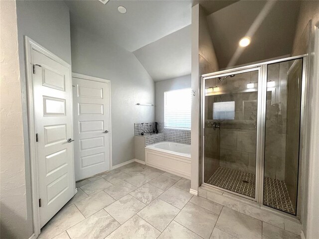 bathroom featuring lofted ceiling, a shower stall, a bath, and baseboards