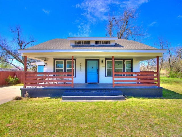 bungalow-style home with a shingled roof, a front yard, and a porch