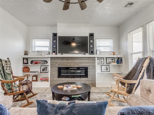 living area with visible vents, wood finished floors, and a healthy amount of sunlight