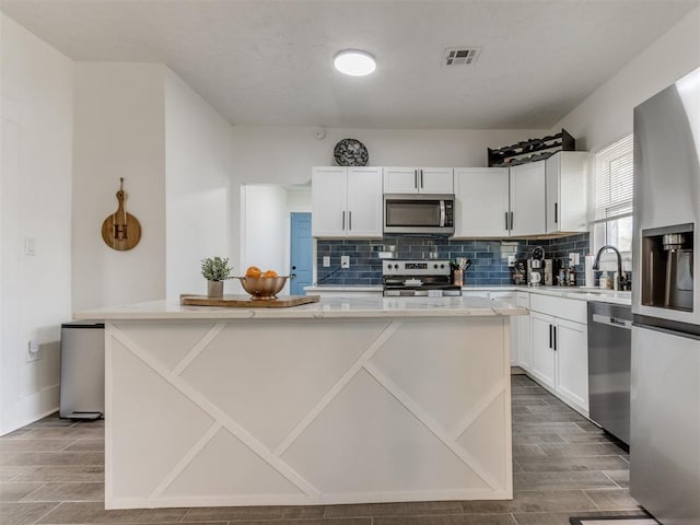 kitchen featuring a center island, white cabinetry, tasteful backsplash, and appliances with stainless steel finishes