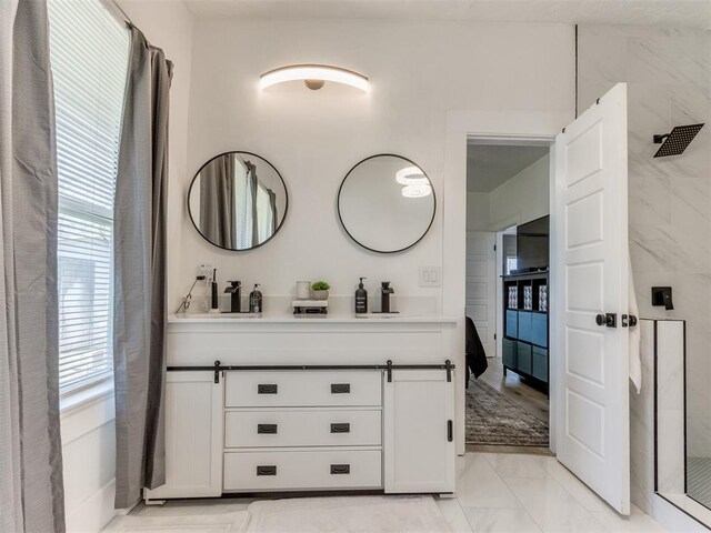 bathroom featuring marble finish floor, double vanity, and a walk in shower