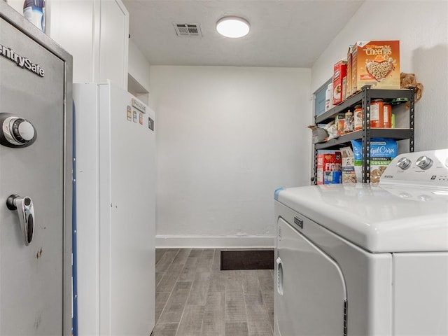 clothes washing area featuring visible vents, baseboards, laundry area, light wood-style floors, and washer and clothes dryer