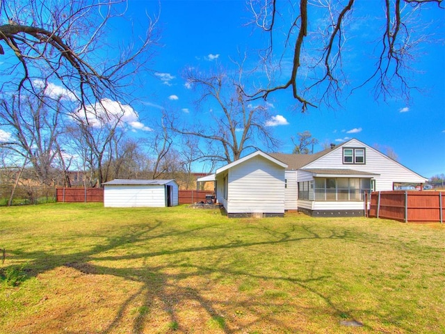 rear view of property featuring an outdoor structure, a fenced backyard, a sunroom, a storage unit, and a yard