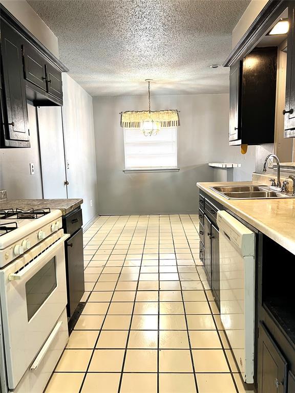 1413 NW 106th St, Oklahoma City, OK 73114 - kitchen with white appliances, a sink, dark cabinetry, a textured ceiling, and light countertops
