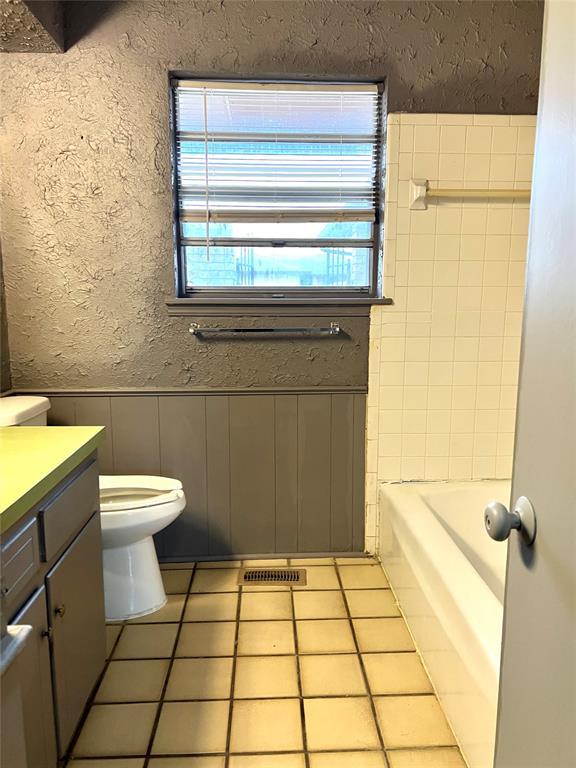 1413 NW 106th St, Oklahoma City, OK 73114 - full bath featuring healthy amount of natural light, vanity, toilet, a tub to relax in, and wainscoting