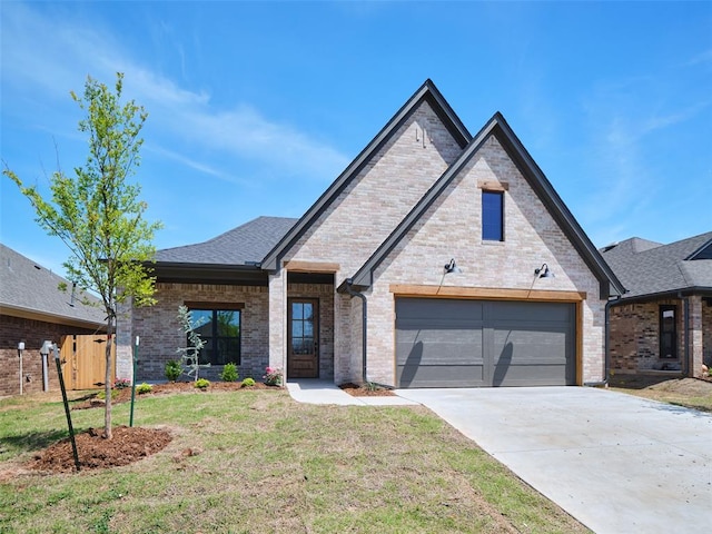 12729 NW 2nd Ter, Yukon, OK 73099 - french country home featuring concrete driveway, brick siding, an attached garage, and a shingled roof