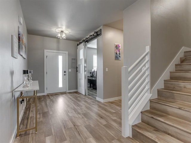 8129 NW 153rd St, Edmond, OK 73013 - foyer entrance with stairway, a barn door, light wood finished floors, and baseboards