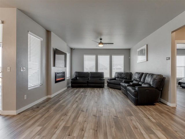 8129 NW 153rd St, Edmond, OK 73013 - living room featuring ceiling fan, wood finished floors, a glass covered fireplace, and baseboards
