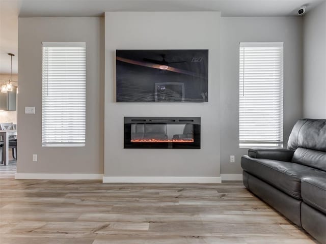 8129 NW 153rd St, Edmond, OK 73013 - living area with light wood-style flooring, a glass covered fireplace, baseboards, and healthy amount of natural light