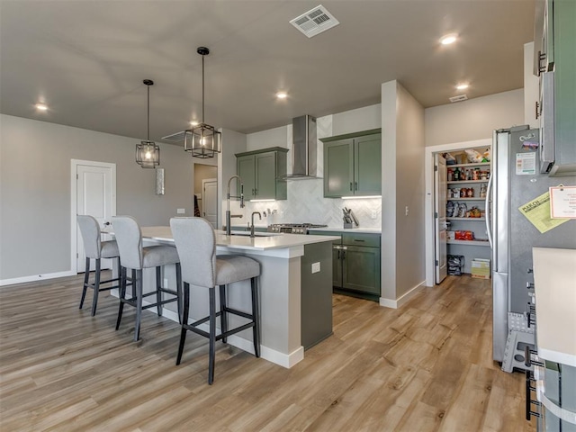 8129 NW 153rd St, Edmond, OK 73013 - kitchen featuring wall chimney exhaust hood, green cabinetry, light wood finished floors, a kitchen bar, and recessed lighting