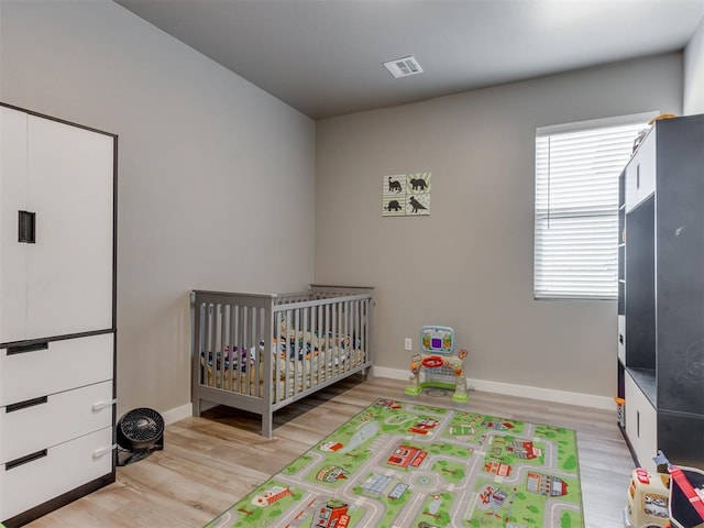 8129 NW 153rd St, Edmond, OK 73013 - bedroom with light wood finished floors, a crib, and baseboards