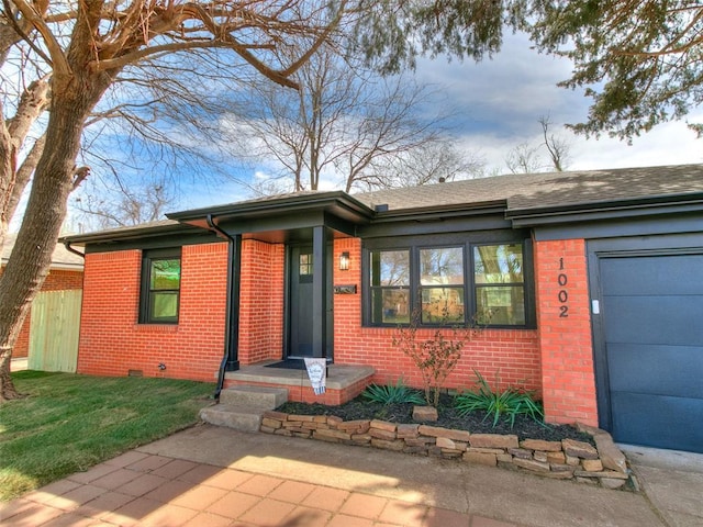 1002 Garver St, Norman, OK 73069 - view of front of house featuring brick siding, a garage, and a front lawn