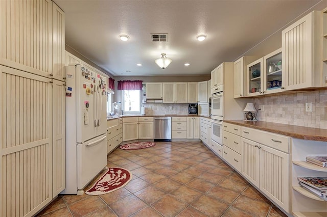 9122 Ns 3540th Rd, Prague, OK 74864 - kitchen with visible vents, white appliances, tasteful backsplash, glass insert cabinets, and cream cabinets