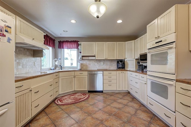 9122 Ns 3540th Rd, Prague, OK 74864 - kitchen featuring white appliances, under cabinet range hood, decorative backsplash, cream cabinets, and light tile patterned flooring