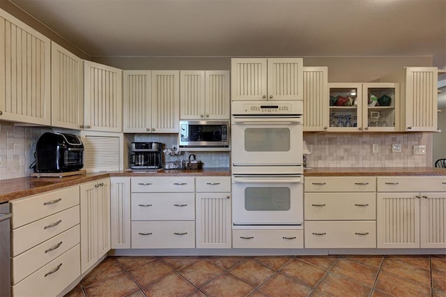 9122 Ns 3540th Rd, Prague, OK 74864 - kitchen with double oven, dark tile patterned floors, cream cabinets, and stainless steel microwave