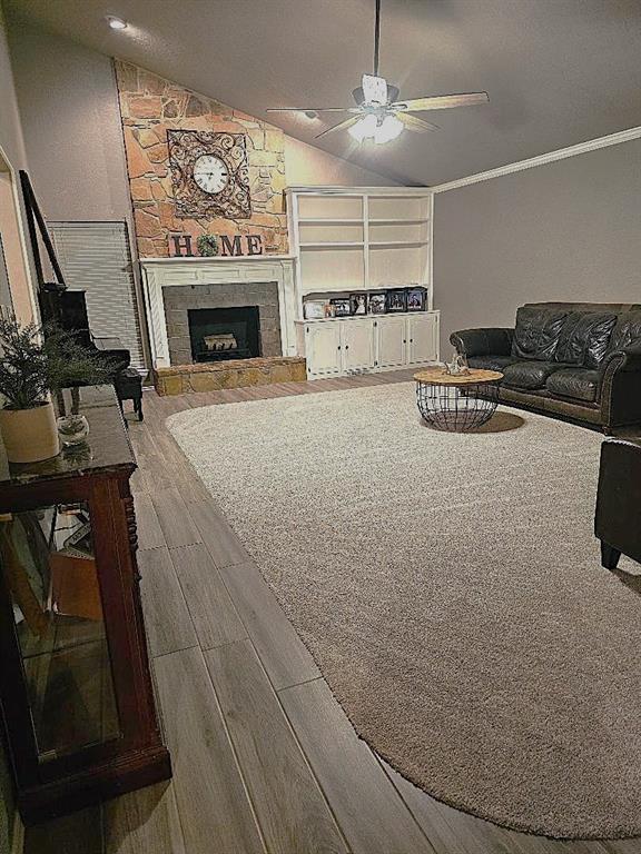 1402 Broad Acres Dr, Norman, OK 73072 - living area with wood finished floors, lofted ceiling, a ceiling fan, crown molding, and a fireplace