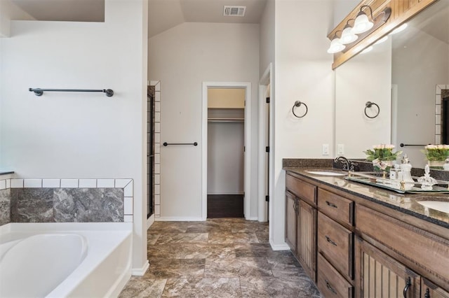 708 Havasu Dr, Norman, OK 73071 - bathroom featuring a bath, lofted ceiling, double vanity, baseboards, and a spacious closet