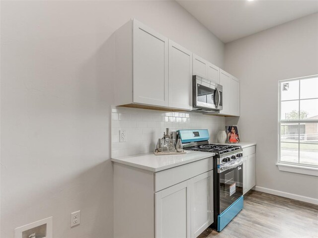 3100 NE 17th St, Oklahoma City, OK 73121 - kitchen featuring stainless steel appliances, backsplash, light countertops, light wood finished floors, and white cabinetry