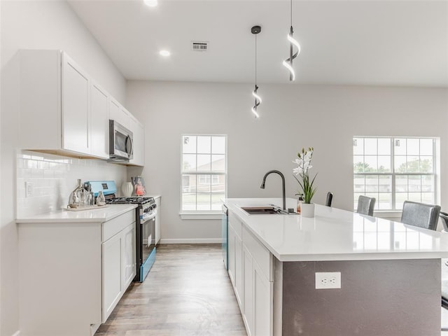 3100 NE 17th St, Oklahoma City, OK 73121 - kitchen featuring stainless steel appliances, a sink, light wood-style floors, white cabinets, and light countertops