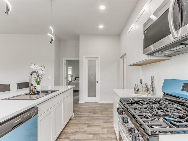 3100 NE 17th St, Oklahoma City, OK 73121 - kitchen with appliances with stainless steel finishes, a sink, light wood-type flooring, white cabinets, and light countertops