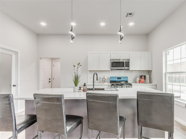 3100 NE 17th St, Oklahoma City, OK 73121 - kitchen with stainless steel appliances, a center island with sink, decorative backsplash, light countertops, and white cabinetry