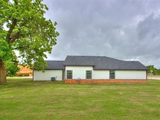 3100 NE 17th St, Oklahoma City, OK 73121 - back of house featuring a yard, cooling unit, and a shingled roof