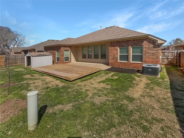 back of house with an outdoor structure, a fenced backyard, brick siding, and central AC unit