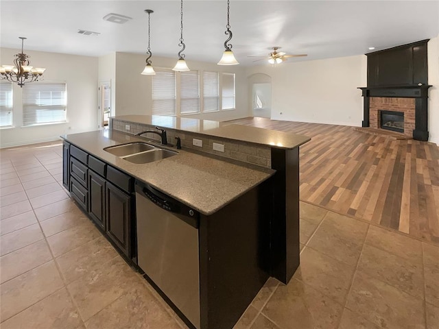 kitchen featuring an island with sink, a sink, dishwasher, open floor plan, and ceiling fan with notable chandelier