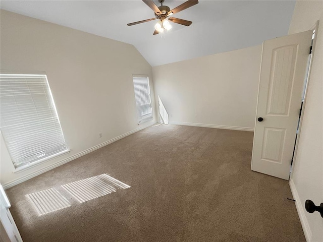 carpeted spare room with a ceiling fan, baseboards, and vaulted ceiling
