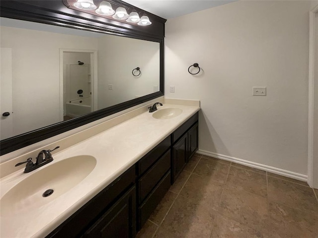bathroom with baseboards, double vanity, a sink, and bathtub / shower combination