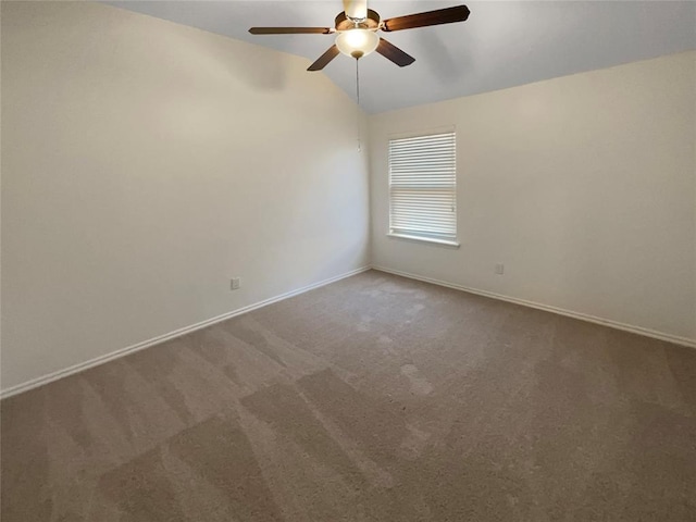 empty room featuring a ceiling fan, carpet floors, baseboards, and vaulted ceiling