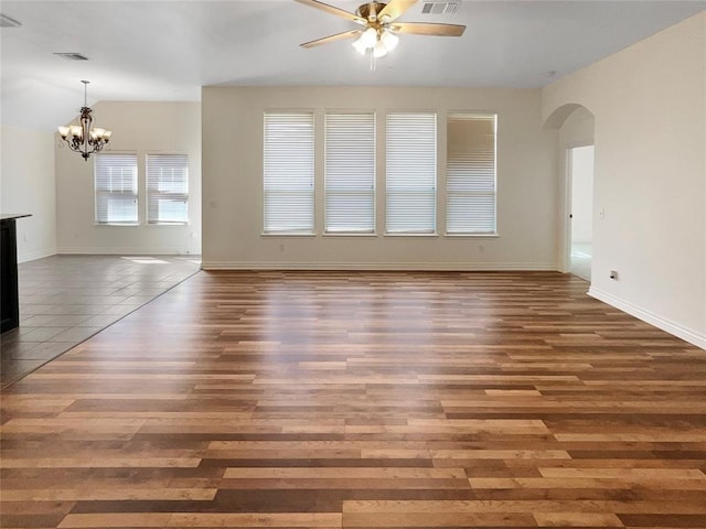 unfurnished living room featuring ceiling fan with notable chandelier, baseboards, arched walkways, visible vents, and wood finished floors