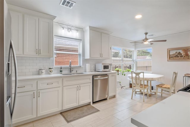 3101 NW 70th St, Oklahoma City, OK 73116 - kitchen with decorative backsplash, white cabinets, visible vents, appliances with stainless steel finishes, and a sink