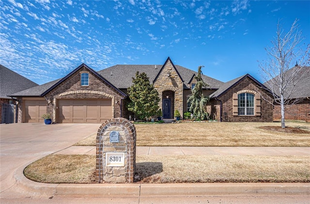 8301 NW 146th St, Oklahoma City, OK 73142 - french country inspired facade with an attached garage, a front yard, brick siding, driveway, and a shingled roof