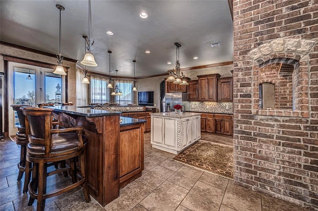 8301 NW 146th St, Oklahoma City, OK 73142 - kitchen with ornamental molding, hanging light fixtures, stainless steel fridge with ice dispenser, a large island, and a kitchen breakfast bar
